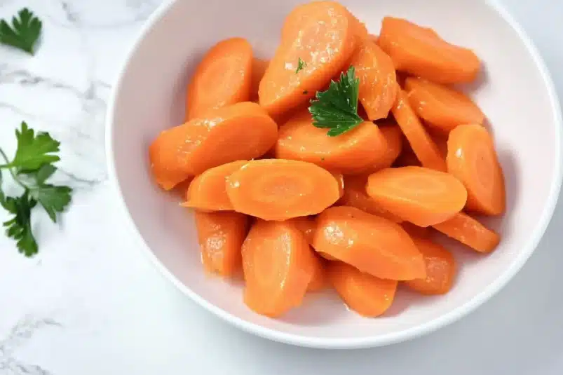 A bowl of tender, honey-glazed carrots roasted to perfection, garnished with fresh herbs for a burst of flavor.