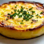 An overhead shot of a casserole dish filled with bubbly baked eggs and cottage cheese, sprinkled with herbs and ready to serve.