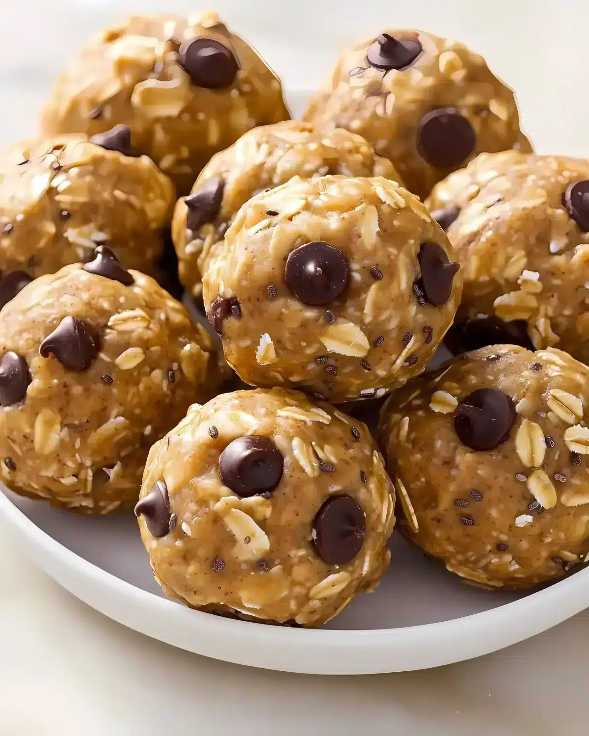 Close-up of traditional oatmeal chocolate chip energy balls stacked on a white plate
