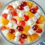 Finished fruit salad with Cool Whip in clear glass bowl