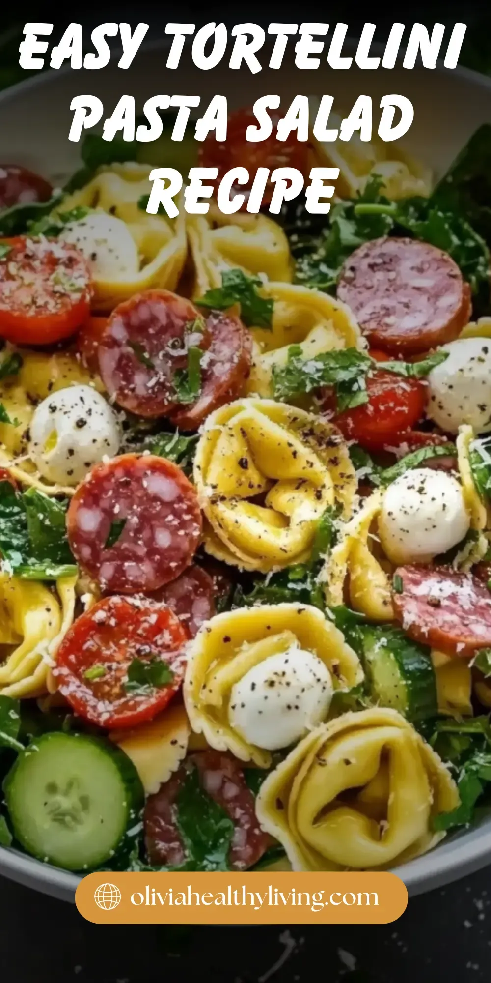 Delicious tortellini pasta salad with mozzarella balls, salami, cucumber, and fresh spinach, sprinkled with black pepper