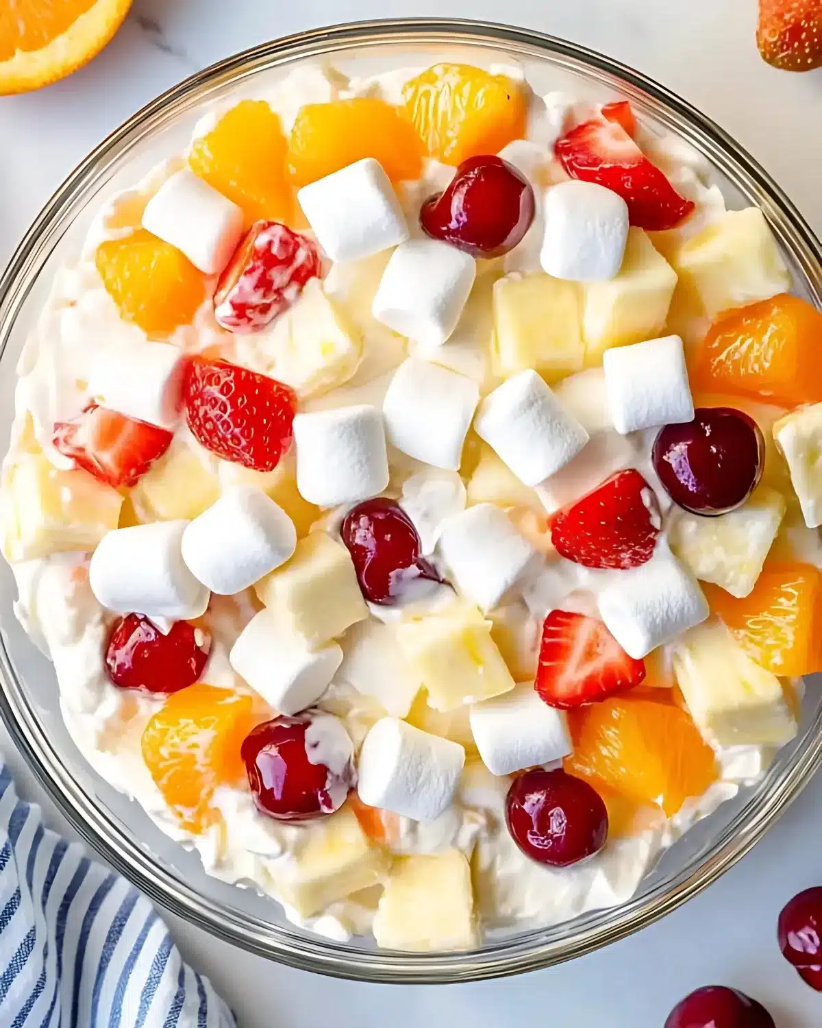 Overhead view of fruit salad with Cool Whip in glass bowl