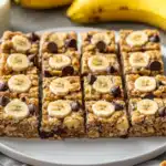 Healthy banana peanut butter oatmeal bars with fresh bananas in the background