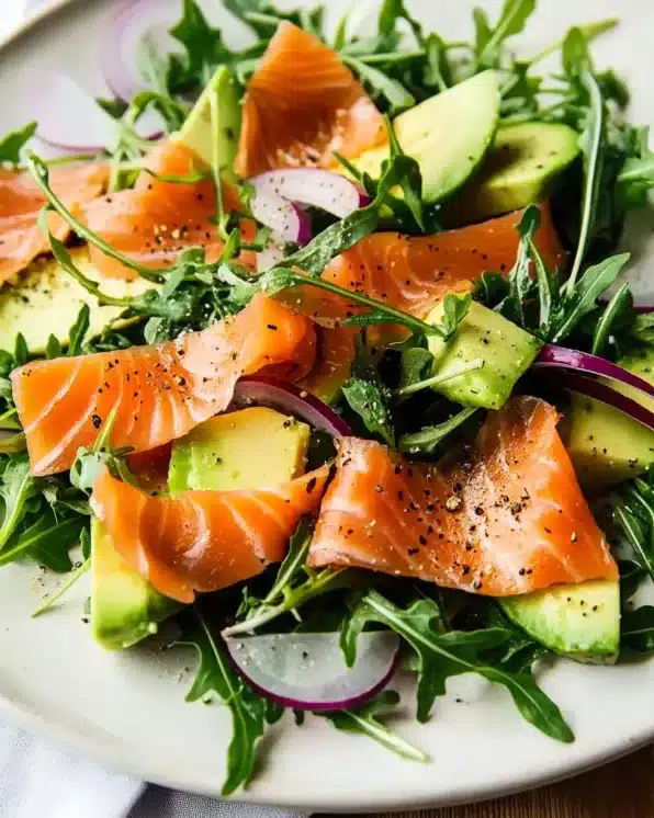 Close-up angled view of smoked salmon and avocado salad with arugula showcasing texture and detail