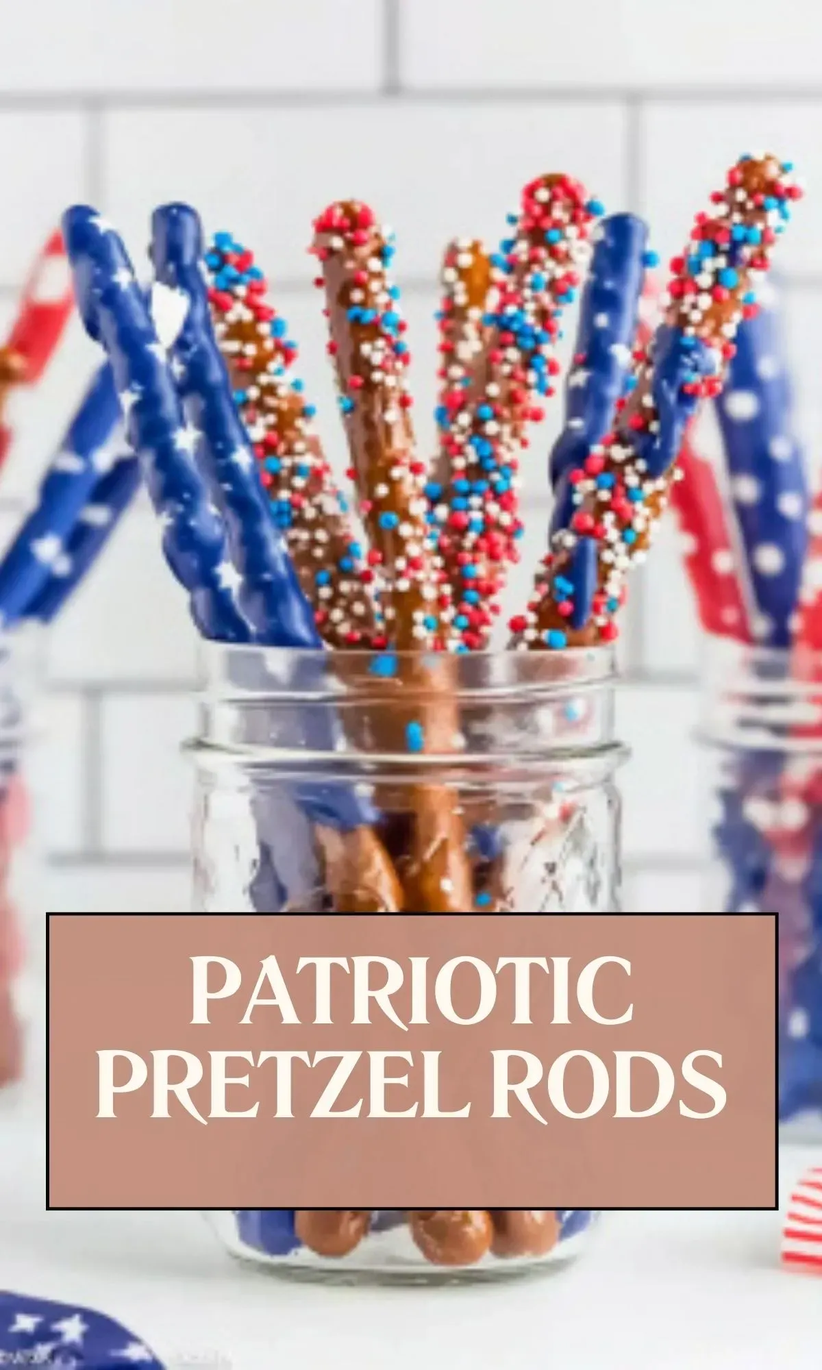 Close-up of patriotic pretzel rods in clear glass jar showing chocolate-covered tips with red, white, and blue sprinkles, with text overlay reading 'PATRIOTIC PRETZEL RODS' against white tile background