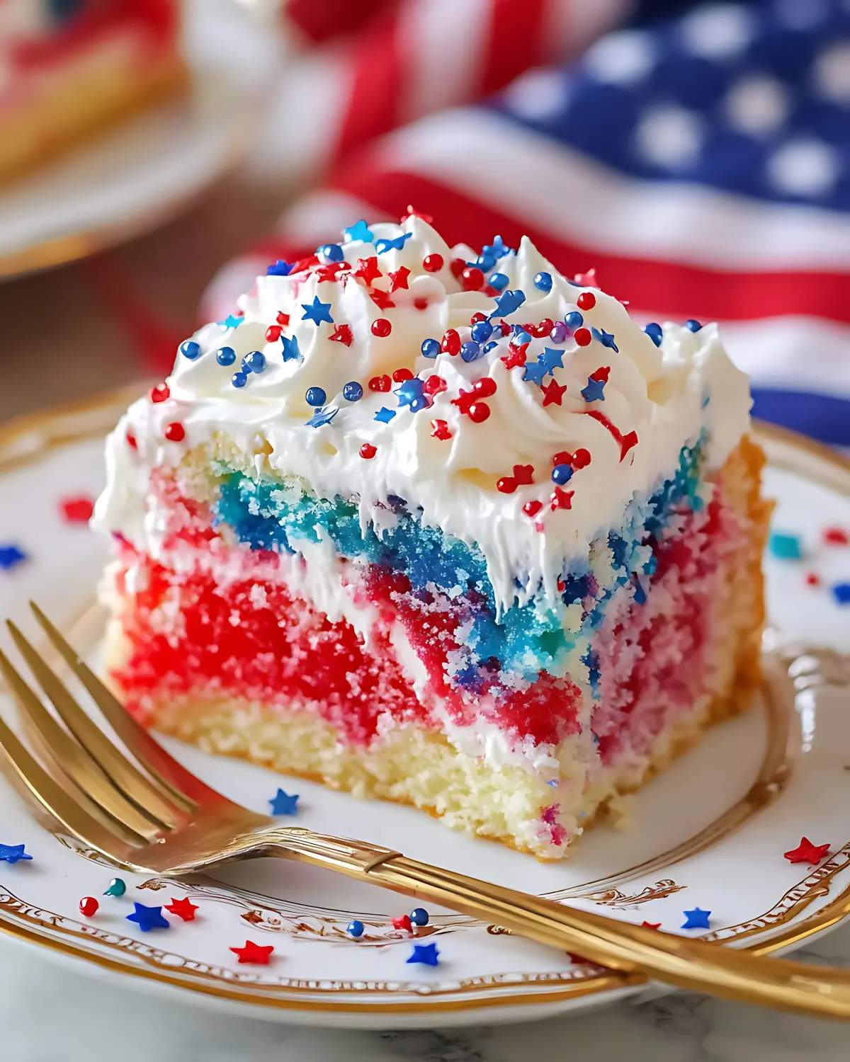 Slice of patriotic poke cake with red and blue jello pockets, topped with whipped cream and star sprinkles.