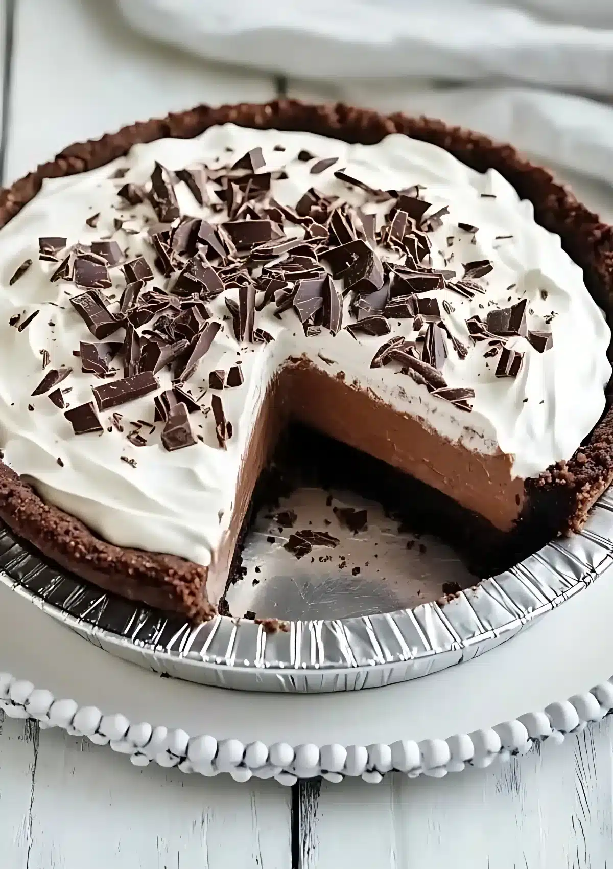 Chocolate pie with cookie crust on a cooling rack showing layers of chocolate filling and whipped cream topped with chocolate shavings