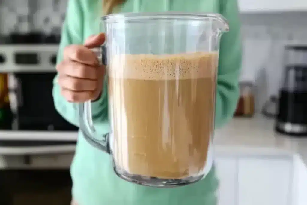  A blender jar full of frothed coffee, ready to be poured into a mug.