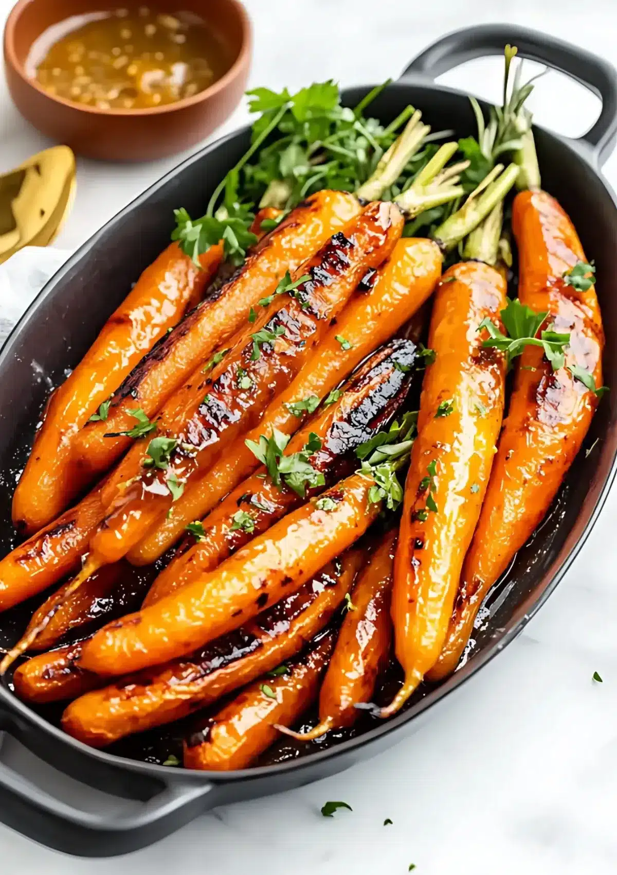 Perfectly grilled carrots with brown butter in an oval serving dish, showcasing caramelized edges and fresh parsley garnish