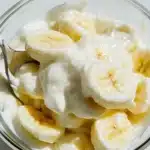 Overhead shot of banana salad in a bowl with mayonnaise and a spoon