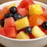 Beautiful tropical fruit salad with watermelon, pineapple, and blueberries mixed in white serving bowl