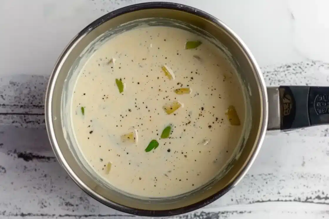 Creamy white sauce with garlic and herbs in stainless steel pan for dairy free creamed spinach