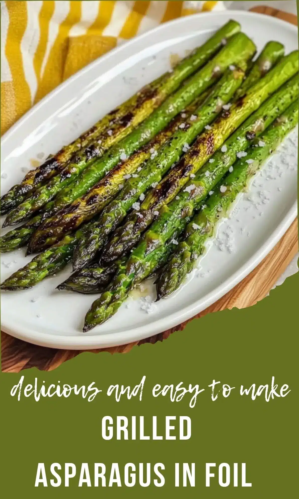 Grilled asparagus with char marks on white oval dish with yellow striped kitchen towel background