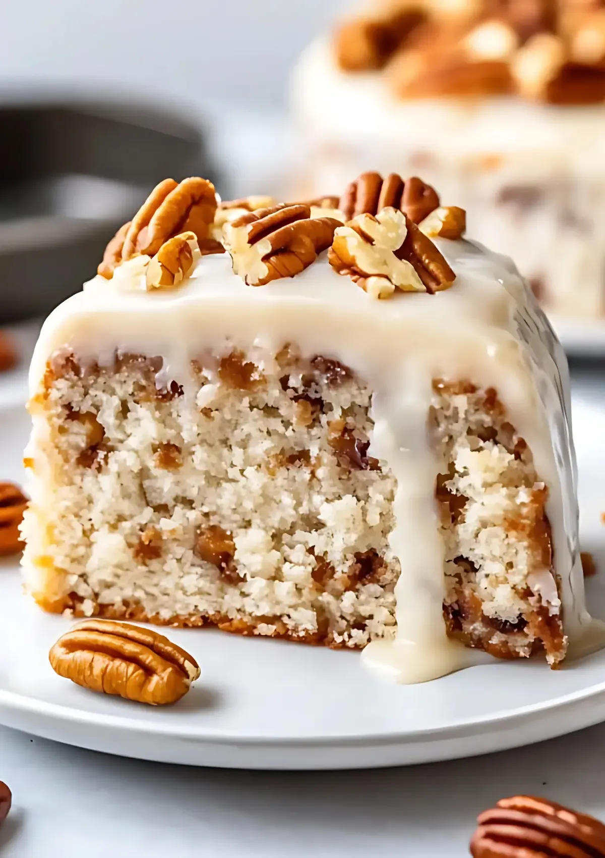 Close up of butter pecan cake slice showing tender crumb texture with pecans and vanilla glaze