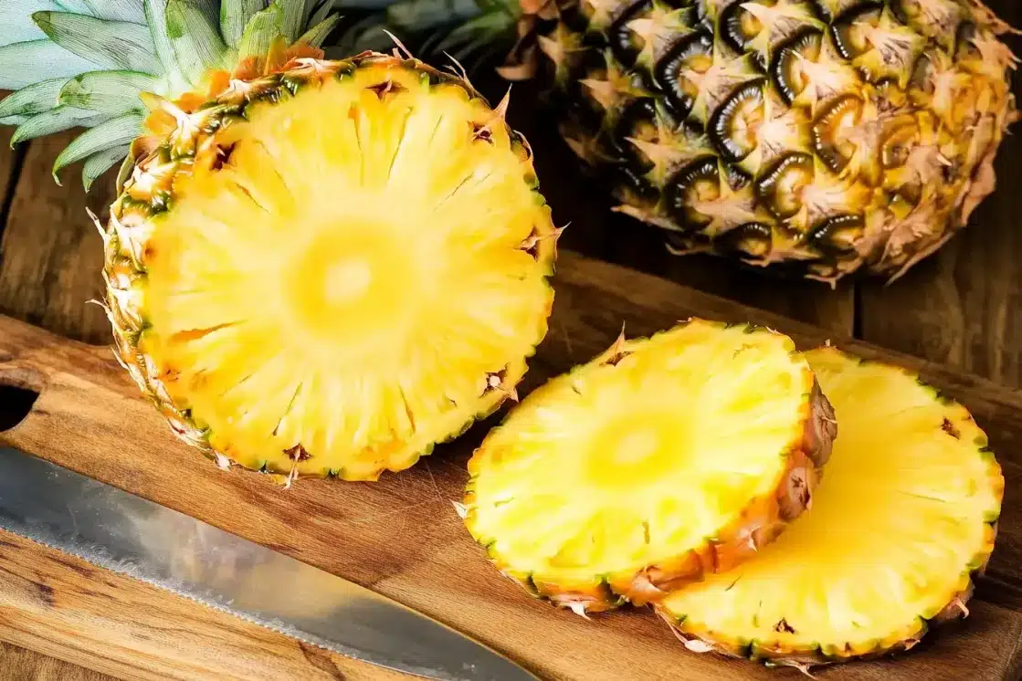 Fresh pineapple cut into rings and chunks on cutting board, key ingredient for tropical fruit salad