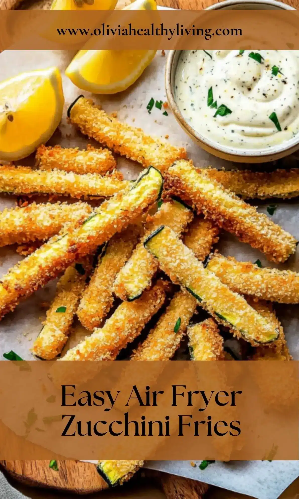 Overhead view of air fryer zucchini fries with lemon wedges and creamy dipping sauce on wooden cutting board