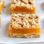 Cut apricot oatmeal bars displaying thick apricot preserved layer between golden oat crumble base and topping
