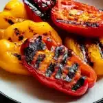 Perfectly grilled bell peppers on white plate showing ideal char marks and tender texture