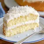 Individual serving of coconut cloud cake on blue-rimmed plate with fork ready to eat