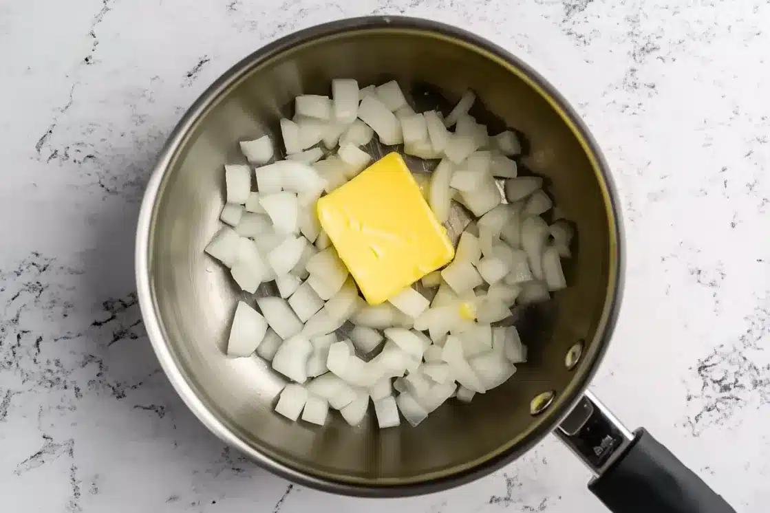 Diced onions and yellow vegan butter in stainless steel pan ready for sautéing