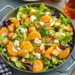 Elegant mandarin orange salad presentation with mixed greens, orange segments, almonds and feta cheese with table setting