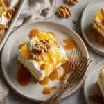 Sliced pumpkin caramel poke cake pieces on plates with caramel sauce dripping and chopped walnuts, served with gold forks