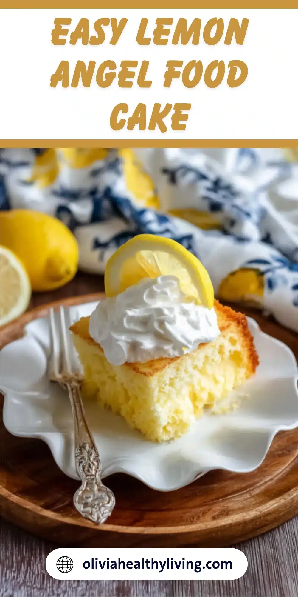 A slice of fluffy lemon angel food cake topped with whipped cream and a lemon slice on a white scalloped plate with fresh lemons in the background
