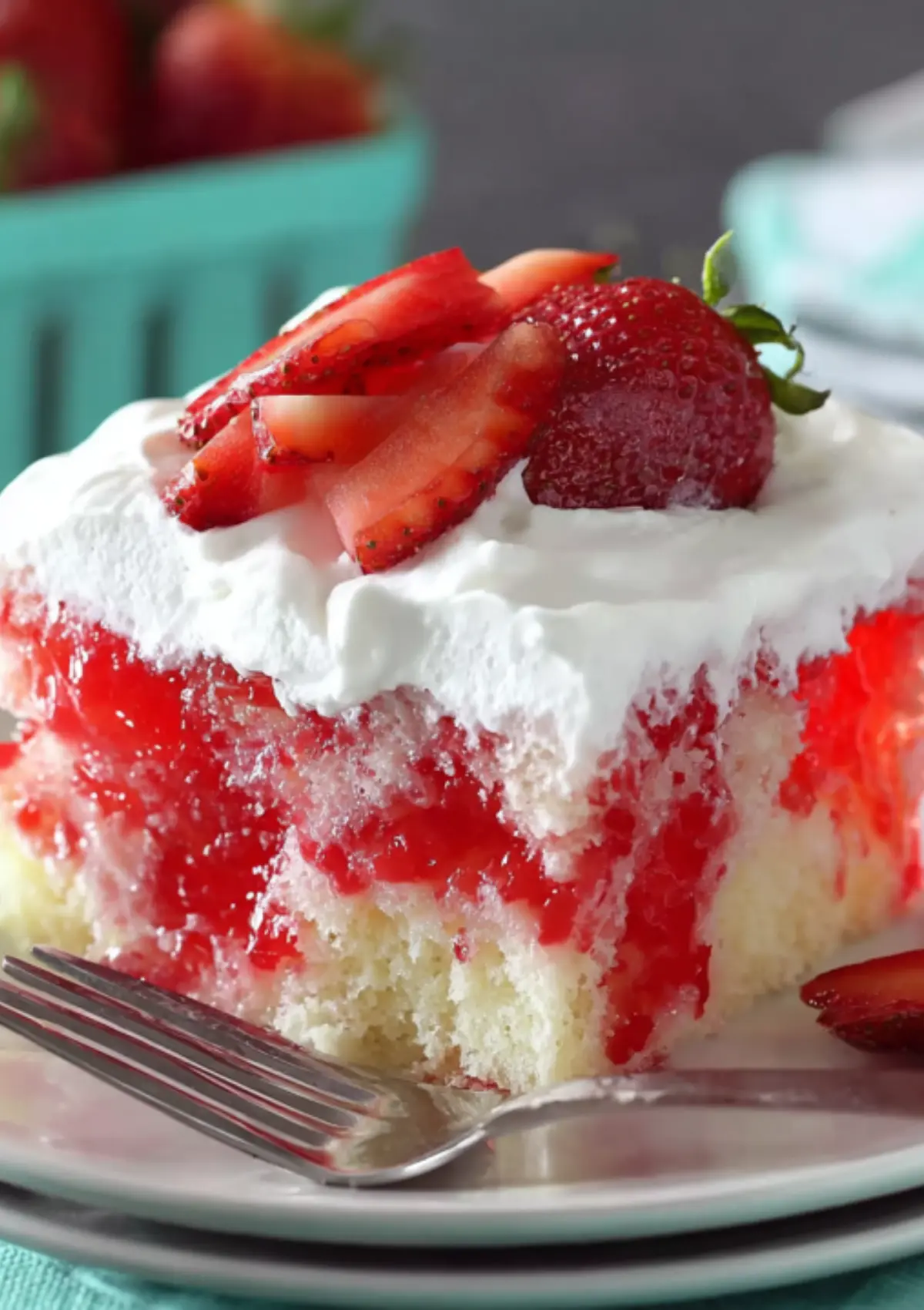 Extreme close-up of strawberry cake slice showing marbled red and white layers with fresh strawberry slices on white frosting
