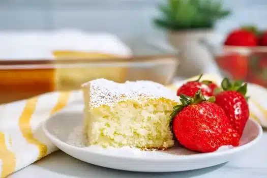 A thick slice of fluffy vanilla cake with a side of strawberries, ready to be enjoyed.