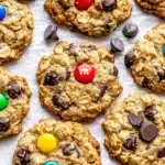 Baked oatmeal cookies with M&M candies, chocolate chips and raisins cooling on parchment paper