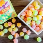 Frozen grapes with Jell-O coating in container next to Sour Apple Nerds candy box, showing the candy-like appearance of the finished recipe