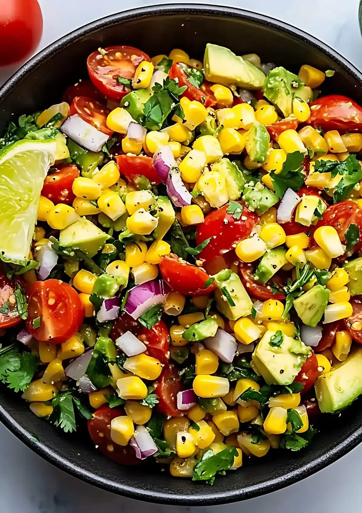 Close-up of vibrant corn tomato avocado salad with diced vegetables and fresh cilantro garnish