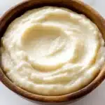 Smooth and creamy Lebanese garlic sauce (Toum) in a wooden bowl on marble background