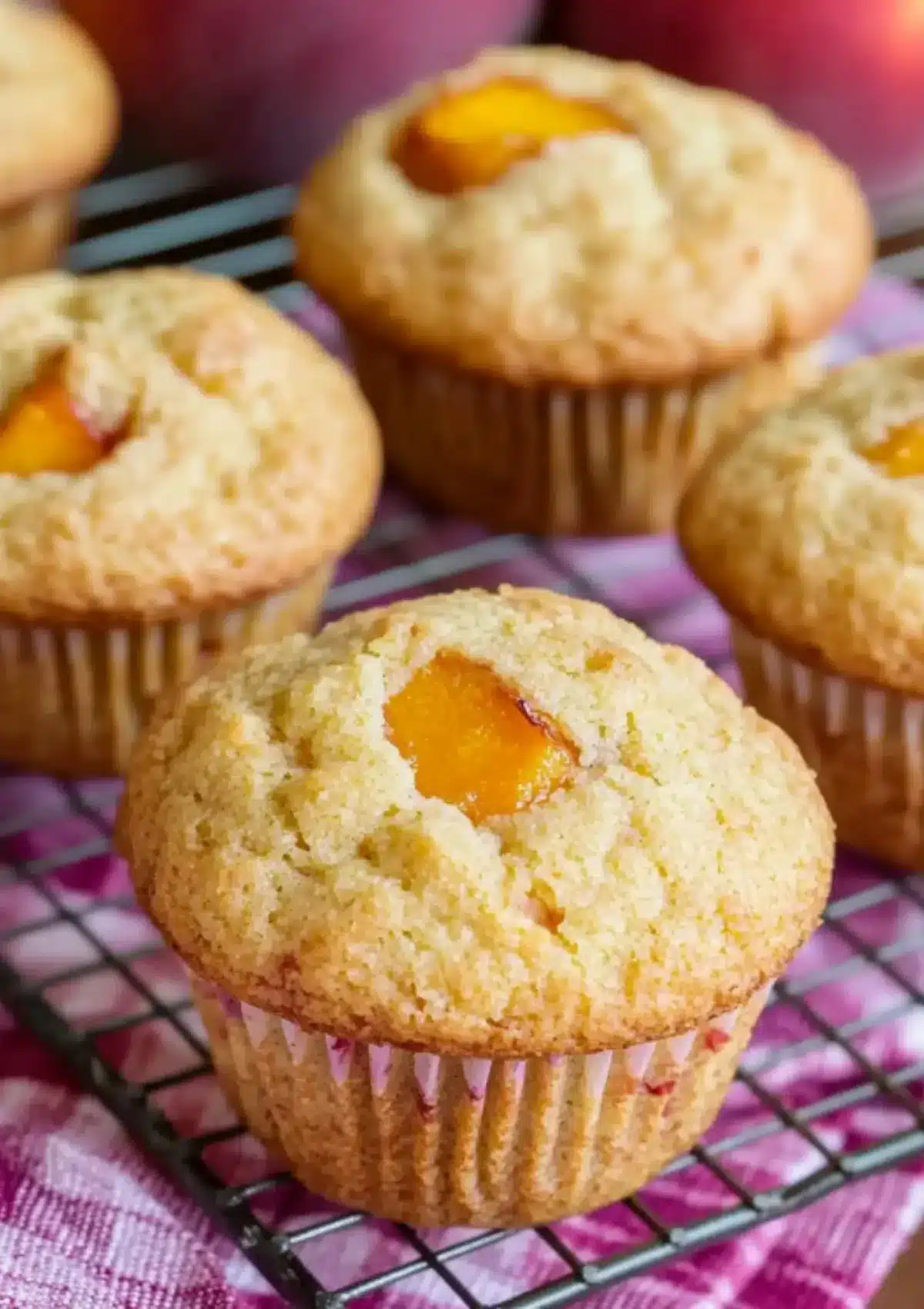 Close-up of peach cobbler muffin on cooling rack showing tender crumb texture and peach pieces