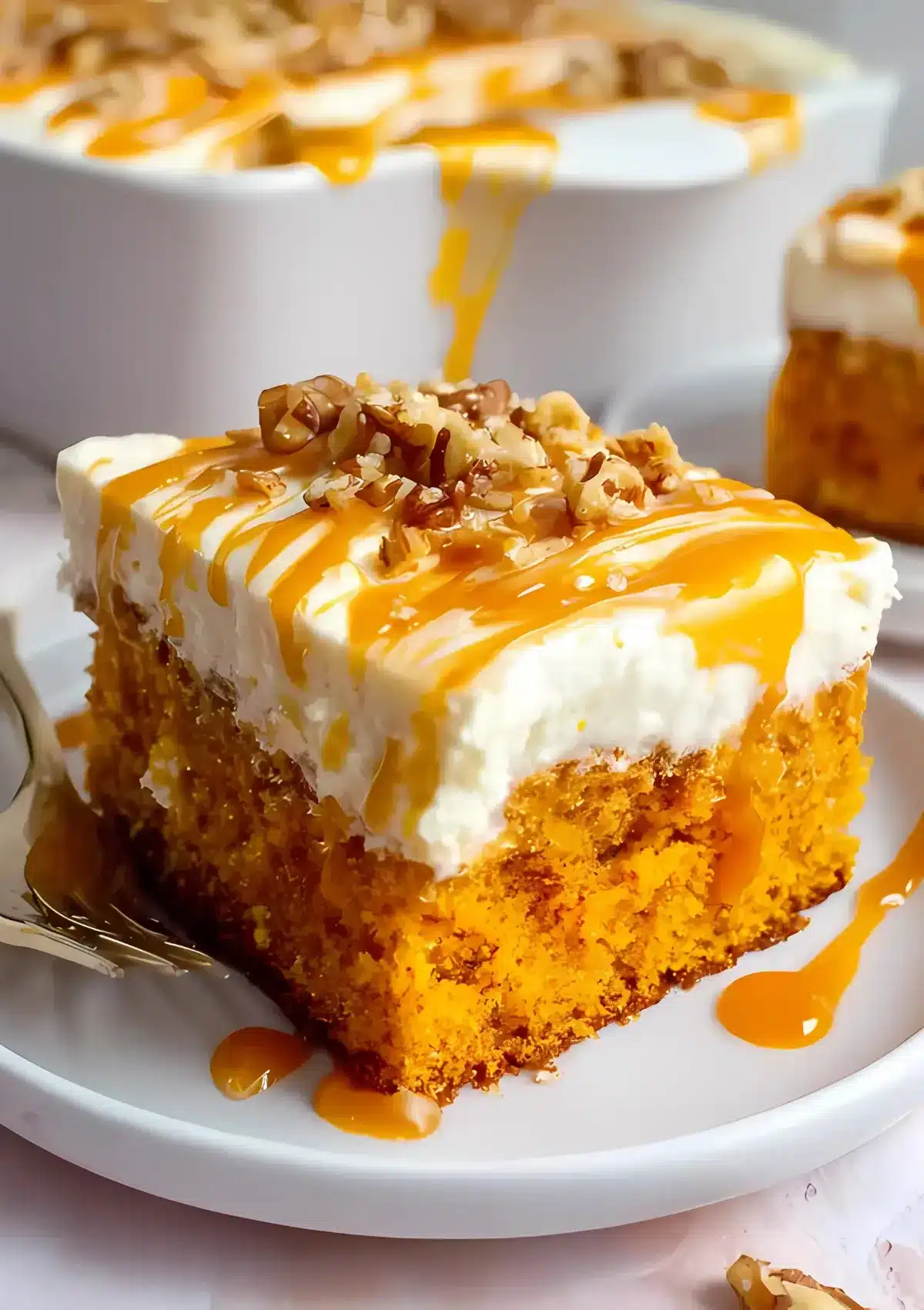 Close-up of pumpkin caramel poke cake slice showing moist orange cake layers with cream cheese frosting and caramel drizzle