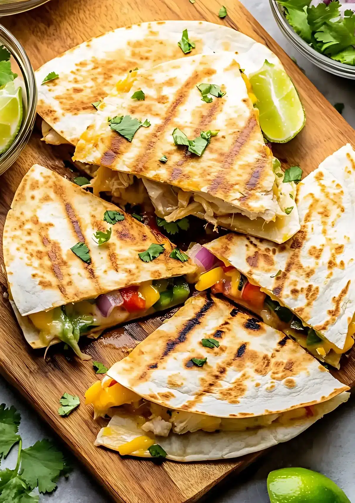 Golden brown chicken quesadillas with grill marks cut into triangles showing melted cheese, chicken and vegetable filling