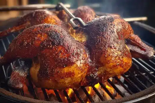 Smoked whole turkey on grill with crispy skin and inserted meat thermometer.