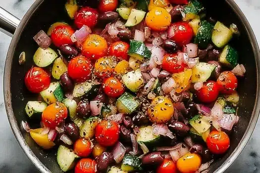 Close-up of stuffed zucchini boats filled with feta, cherry tomatoes, and olives, baked to golden perfection.
