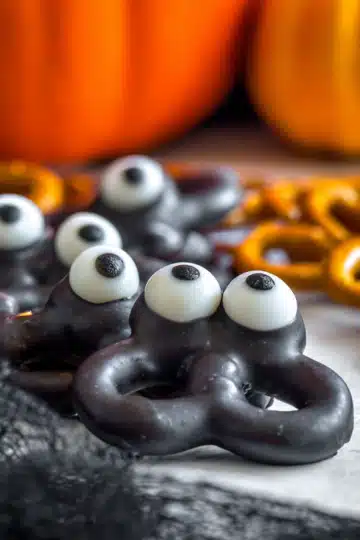 Close-up of chocolate-covered pretzel monsters with three candy eyes each