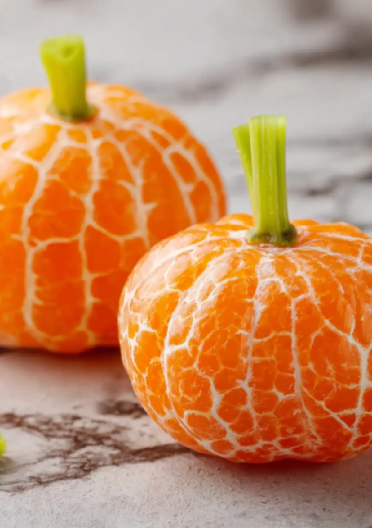 Close-up of orange segments shaped like pumpkins with celery stem garnishes