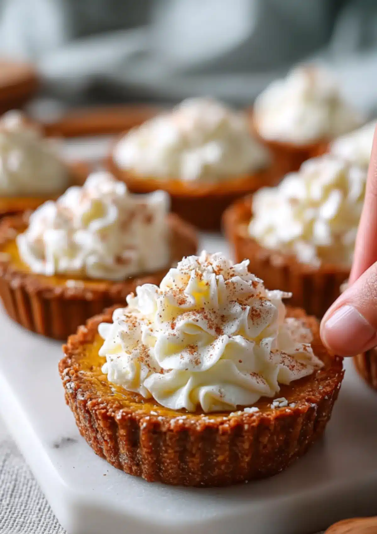 Hand holding a pumpkin protein pie with whipped cream
