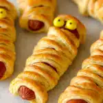 Multiple mummy hot dogs arranged on light surface