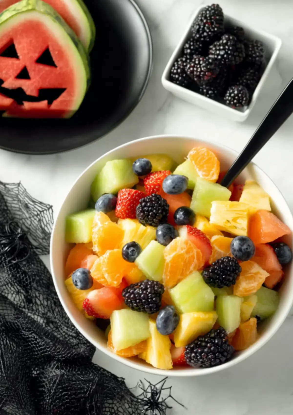 White bowl of Halloween fruit salad with blackberries