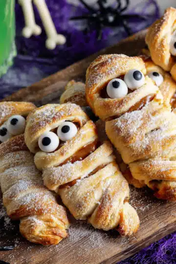 Wide shot of multiple mummy pastries on wooden serving board