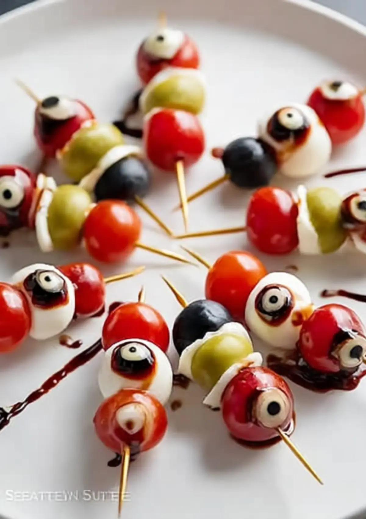Close-up of bleeding eyeball caprese bites on toothpicks with balsamic glaze