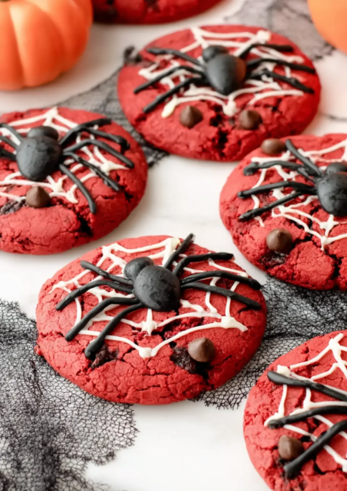 Detailed view of red velvet cookies with white web patterns and black spider toppers