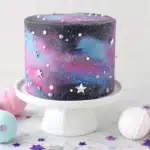 Galaxy cake on white pedestal stand with pastel macarons and purple star decorations