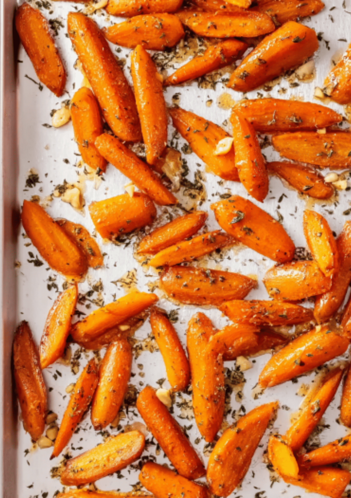 Roasted carrots on baking sheet with herbs and garlic