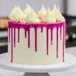 Side view of white cake with pink drips and buttercream decoration