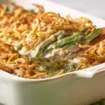 Spoon scooping creamy green bean casserole with crispy topping